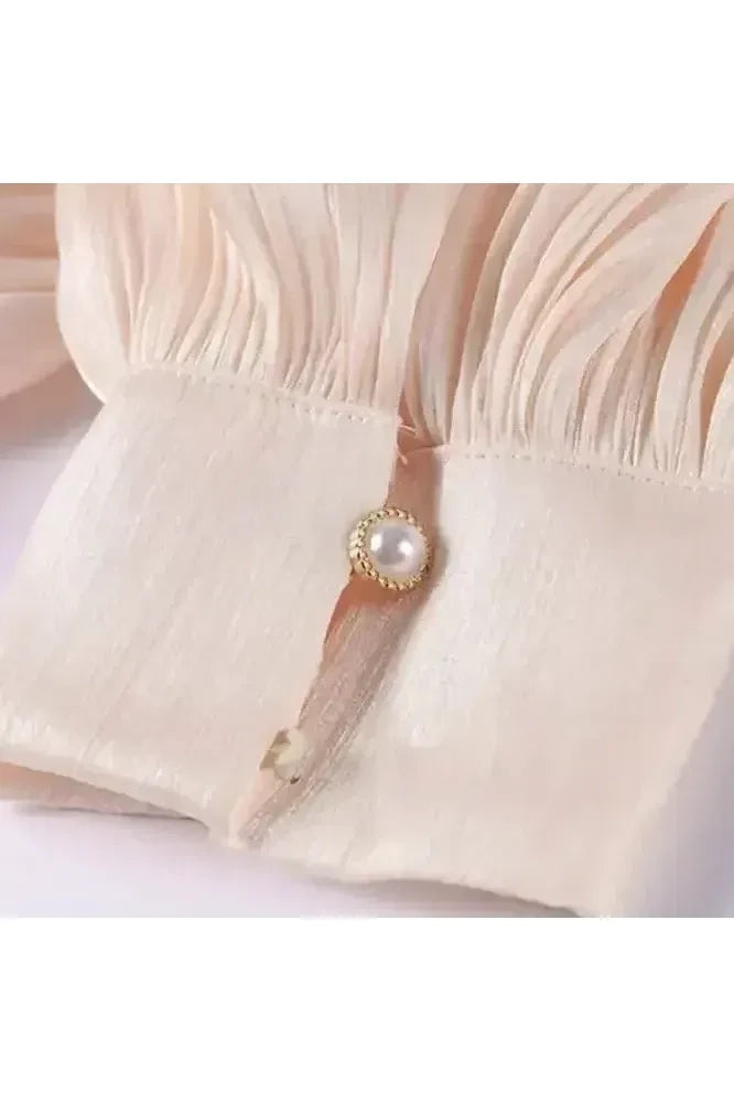 Detailaufnahme des Éloïse Plissee Kleids mit elegantem Plisseestoff und Perlenknopf.