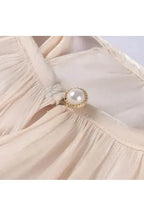 Detailansicht des Éloïse Plissee Kleids mit elegantem Knopf und plissiertem Stoff.