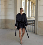 Frau trägt das Éloïse Plissee Kleid in Schwarz mit trendigen Accessoires und elegantem Stil.