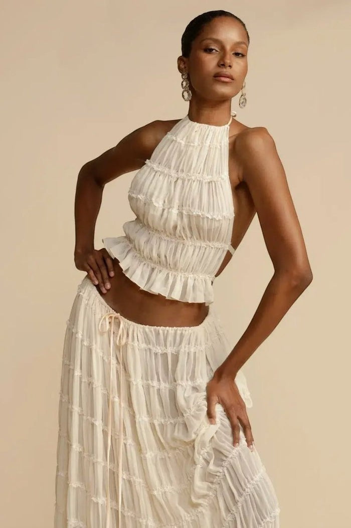 Miraee Paris two-piece set featuring a cream pleated halter top and matching maxi skirt with delicate lace trim